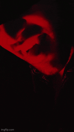 a close up of a person 's face in the dark with a red light behind them