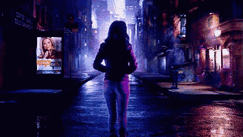 a woman is walking down a street at night with a sign that says cold washing