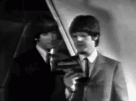two men in suits and ties are standing next to each other in a room .