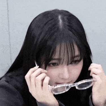 a girl with long black hair and bangs is wearing clear glasses