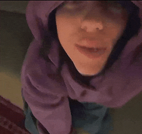 a close up of a person wearing a purple hoodie with a hood .