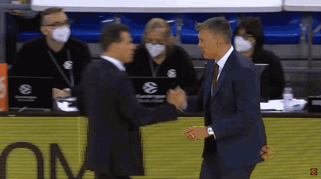 a man in a suit shakes hands with another man in front of an om sign