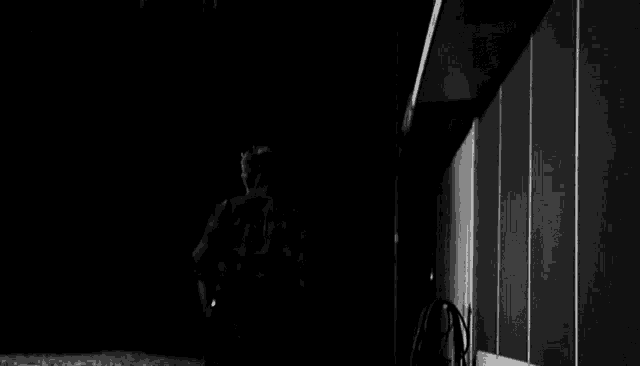 a black and white photo of a man in a wheelchair in a dark room .
