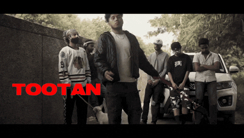 a group of men are standing in front of a car with the word tootan on the bottom right
