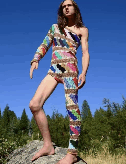 a man standing on a rock wearing a colorful sweater