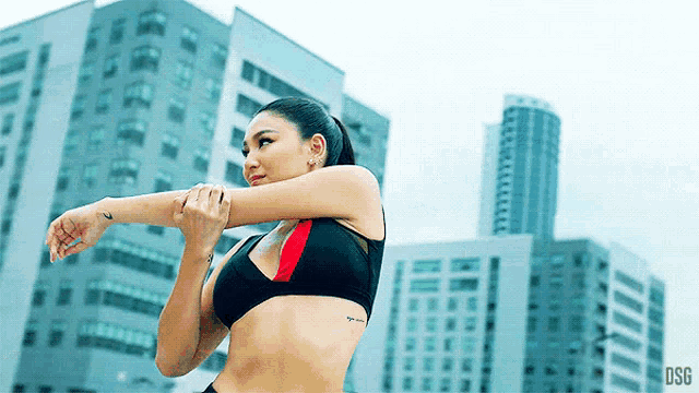 a woman stretches her arms in front of a city skyline and the letters dsg are visible