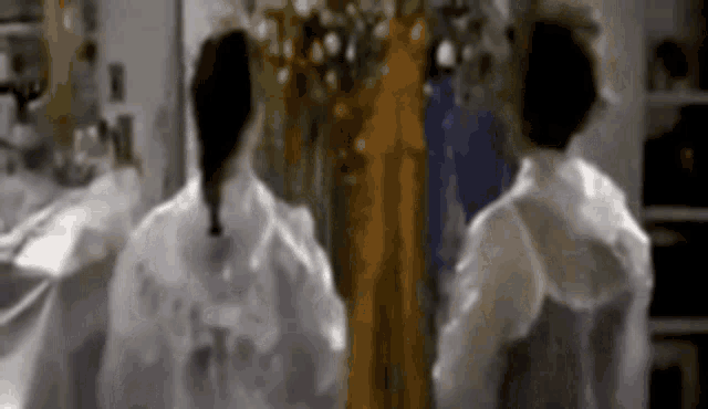 a couple of people standing next to each other in a room wearing white jackets .