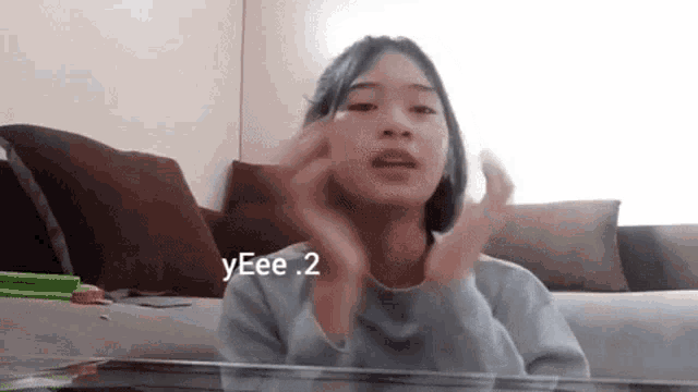 a girl sitting on a couch with a sign that says yeee 2