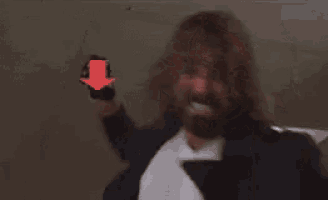a man with a beard is standing in front of a red arrow pointing to the right .