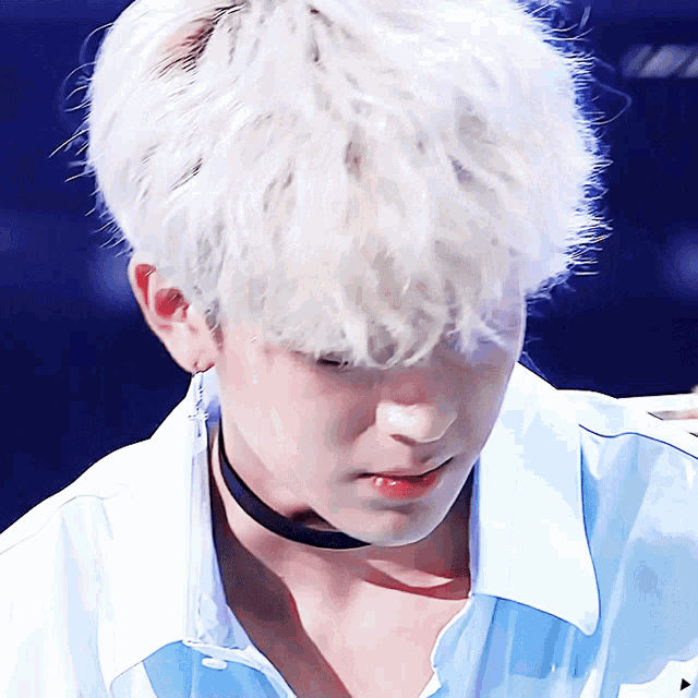a close up of a person 's face with white hair and a choker around their neck
