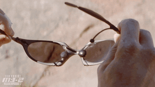 a close up of a person 's hand holding a pair of sunglasses that says tom cruise m-i-e