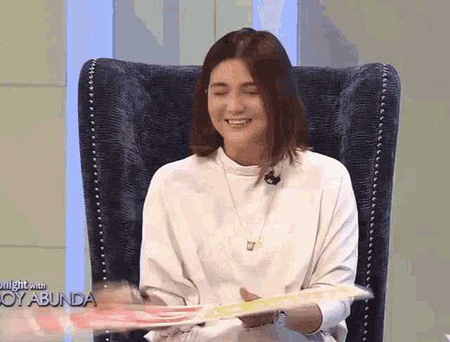 a woman sitting in a chair with a sign that says night with joy abunda on it