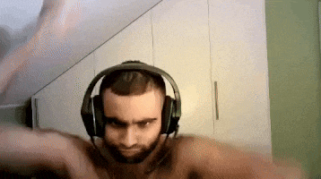 a man without a shirt is wearing headphones and making a funny face .