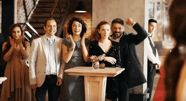 a group of people standing around a wooden table