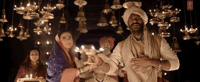 a man in a turban is holding a candle in front of a woman