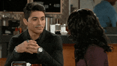 a man and a woman are sitting at a table in front of a sign that says 4:00
