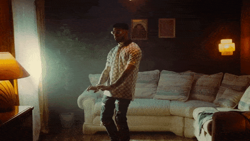 a man is dancing in a living room with a couch and a lamp