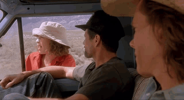 a man and two women are sitting in a car talking to each other