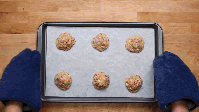 a person wearing blue slippers is holding a baking sheet with cookies on it