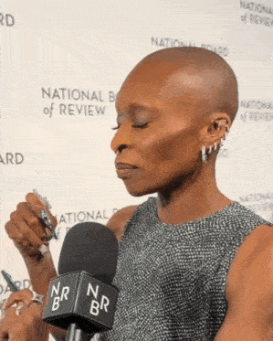 a woman stands in front of a microphone that says national board of review