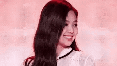 a woman with long black hair is smiling and wearing a white dress .