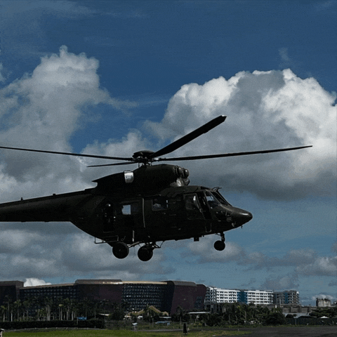 a black helicopter is flying over a city with buildings in the background