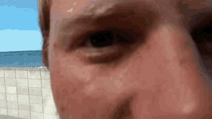 a close up of a person 's face with a brick wall in the background