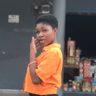 a girl in an orange shirt is standing in front of a store with a sign on the wall that says " no parking "