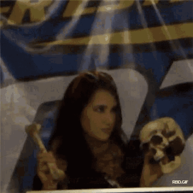 a woman is holding a skull in front of a banner that says rbd gif