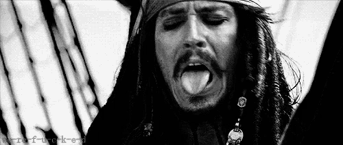jack sparrow from pirates of the caribbean is sticking his tongue out in a black and white photo .