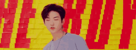 a young man is standing in front of a yellow and red wall with the word love on it .