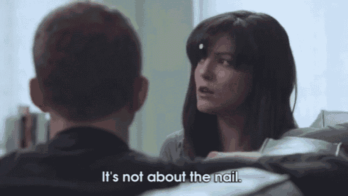 a man and a woman are sitting on a couch and the woman says it 's not about the nail