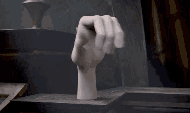 a statue of a hand is sitting on top of a wooden table .