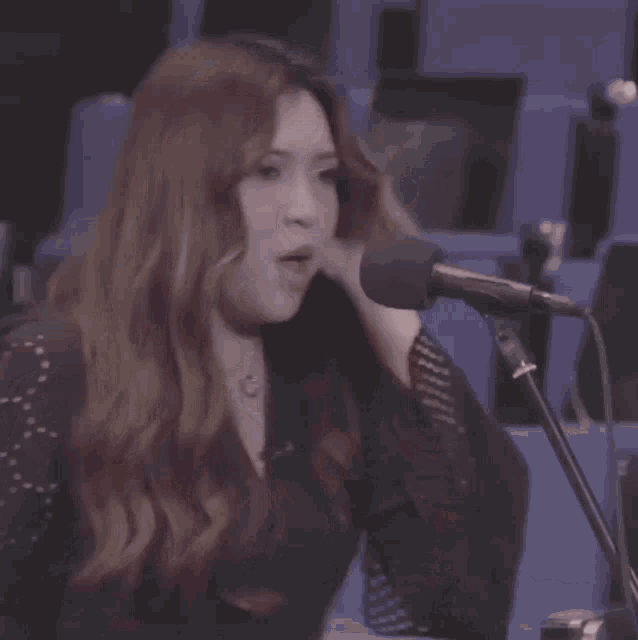 a woman singing into a microphone with chinese characters on the screen