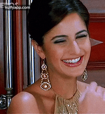 a woman wearing a necklace and earrings is smiling and clapping her hands .