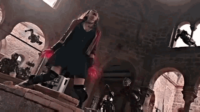 a woman in a black dress and red gloves is standing in a building with arches