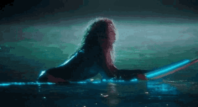 a woman is kneeling in the water with a surfboard .