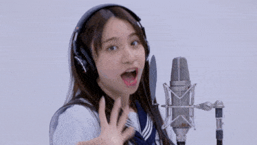 a girl wearing headphones is singing into a microphone with her hands in the air