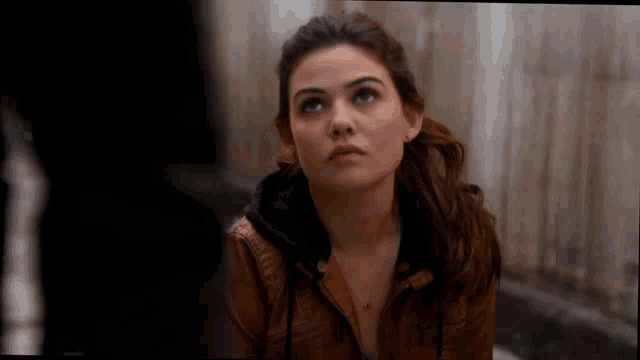 a woman in a brown jacket is looking up