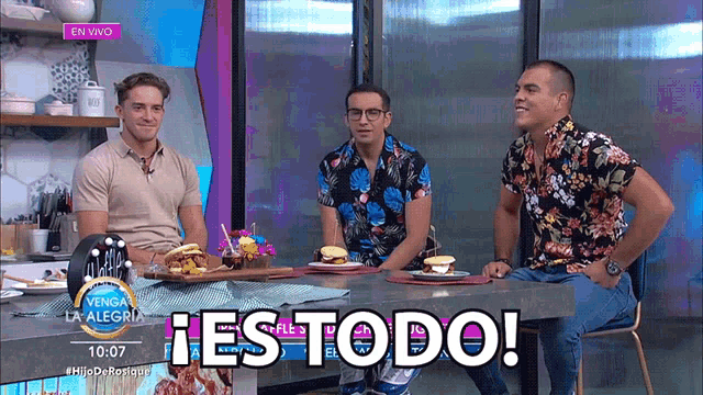 three men are sitting at a table with a sign that says ' es todo '
