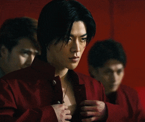 two men are standing next to each other in front of a red wall