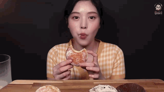a young woman is eating a donut with a bite taken out of it .