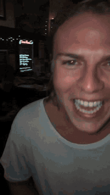 a man in a white shirt is smiling in front of a fridge that says ' coca cola ' on it