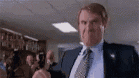 a man in a suit and tie is holding a gun in his hand in a room .