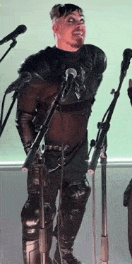 a man in a black suit is standing in front of a microphone .