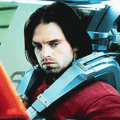 a man in a red shirt is sitting in a car wearing a blue vest .