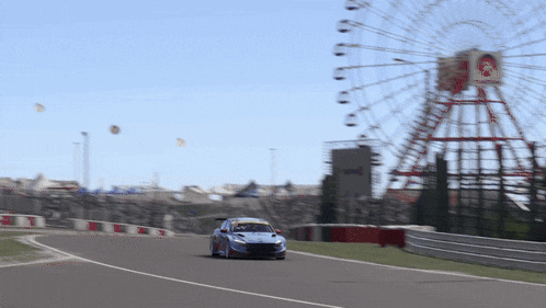 a ferris wheel is in the background of a race track