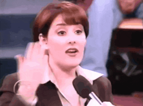 a woman speaking into a microphone with her hand up