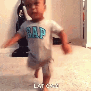 a little boy wearing a gap shirt is walking on the floor .