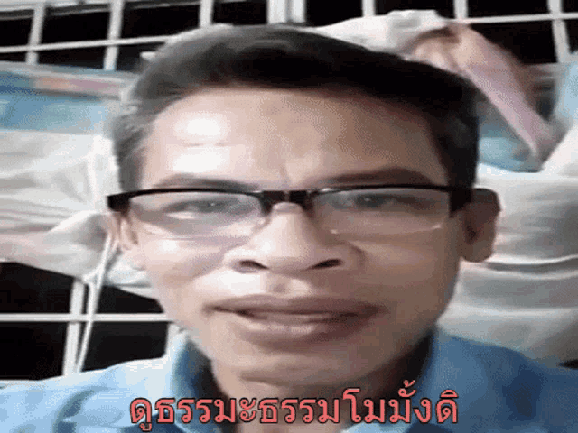 a man wearing glasses and a blue shirt is smiling in a video